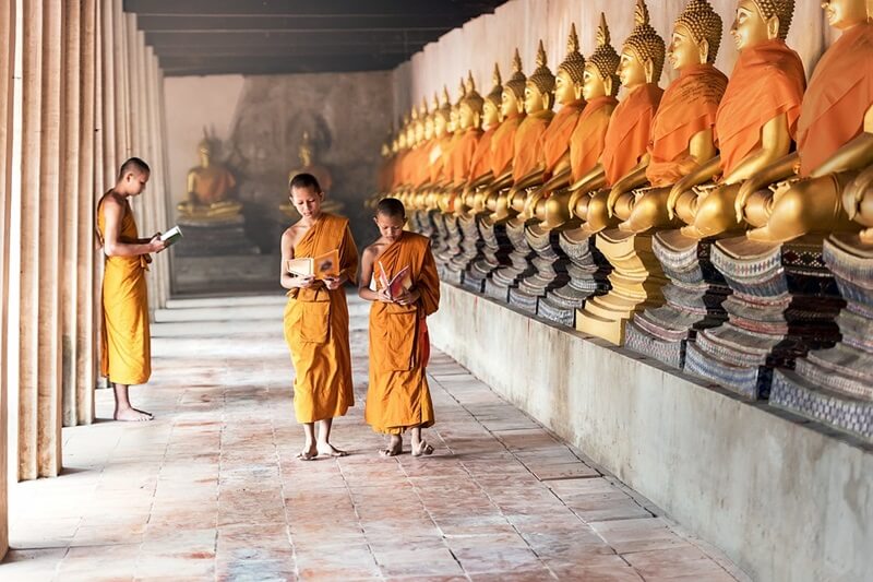 仏像の前を歩く子供の僧侶